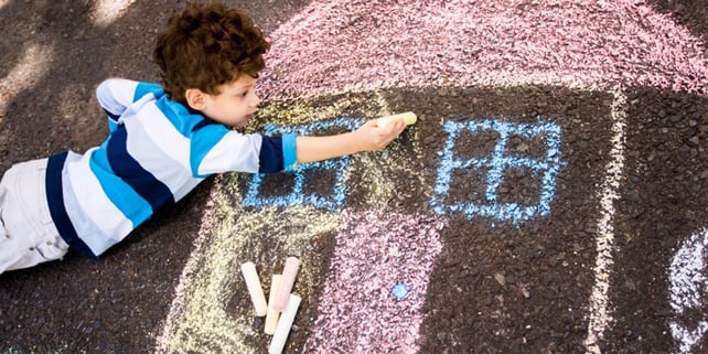 kid drawing chalk house on floor